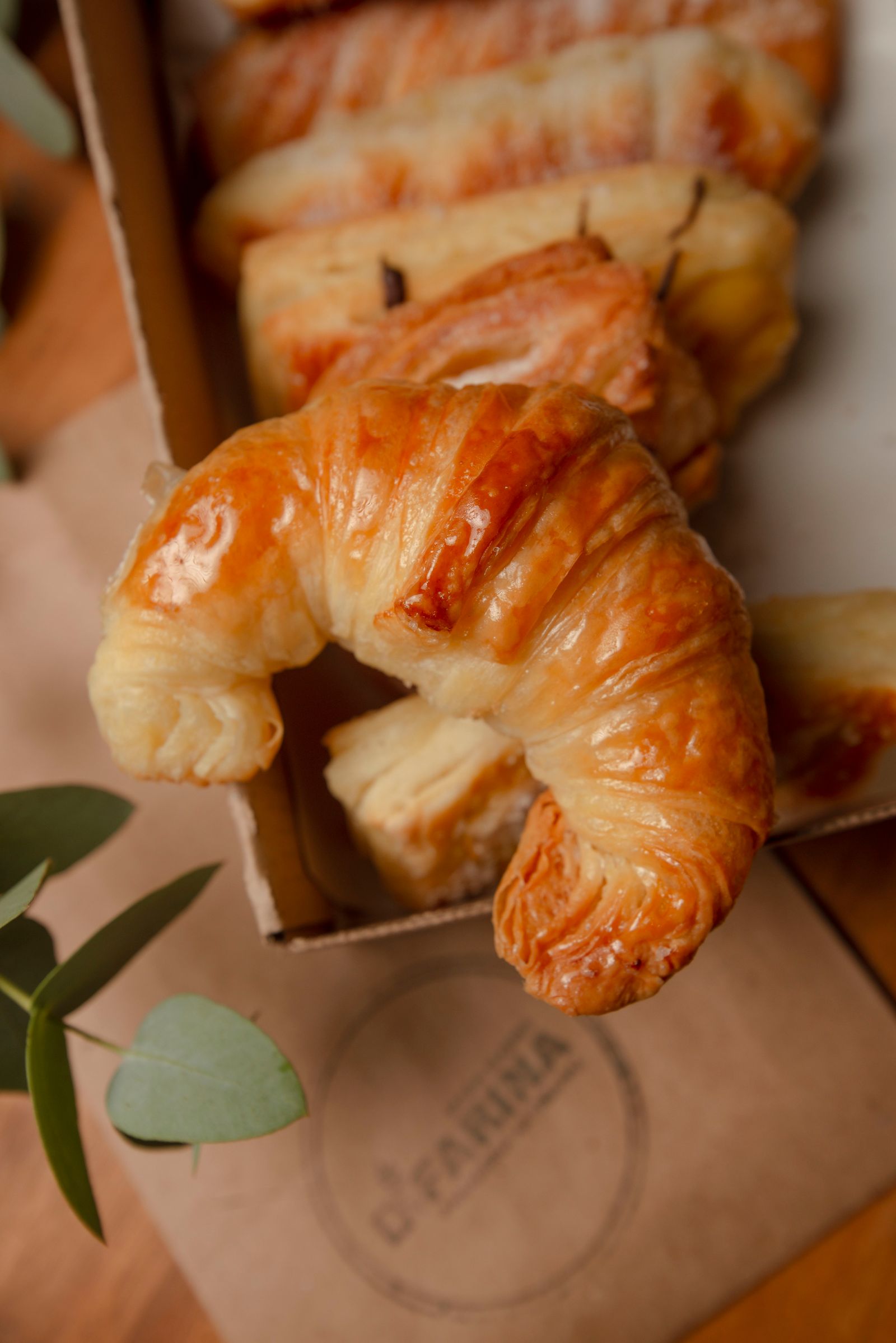 Croissant folhado dourado, feito com manteiga, em embalagem de papel kraft