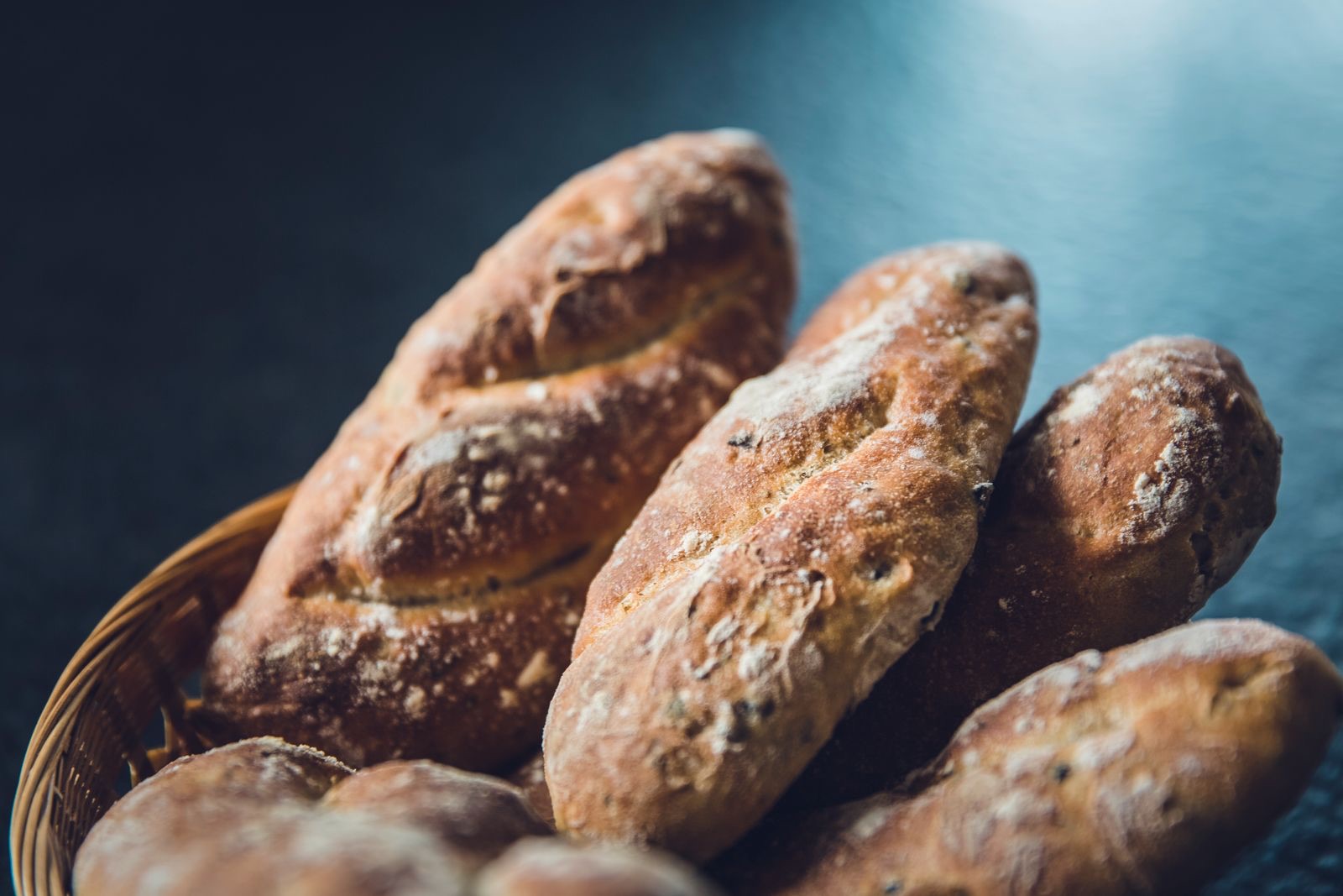 Pães rústicos de fermentação natural em cesto, com casca escura e polvilho de farinha
